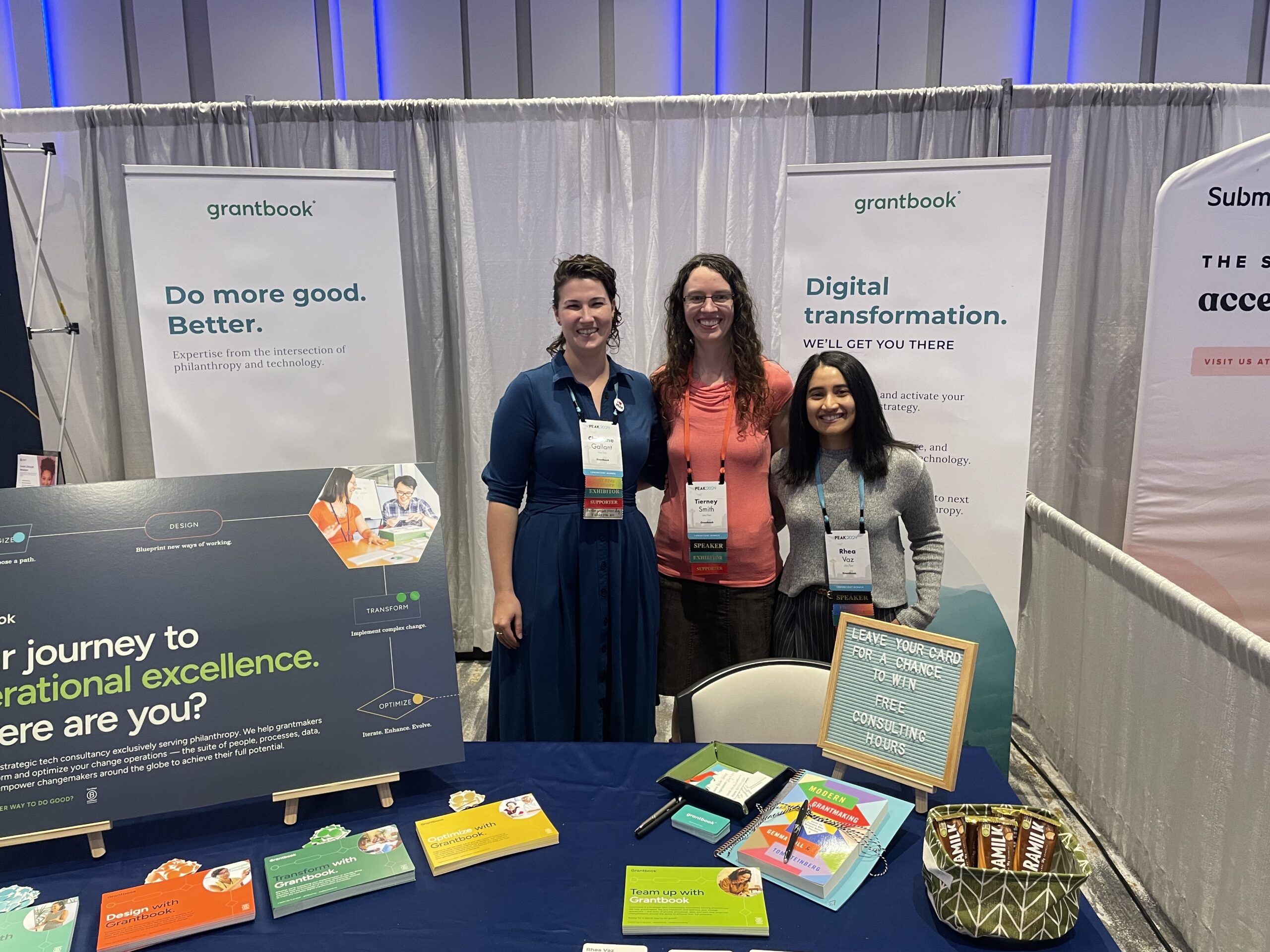 three smiling Grantbook staff stand behind the table booth