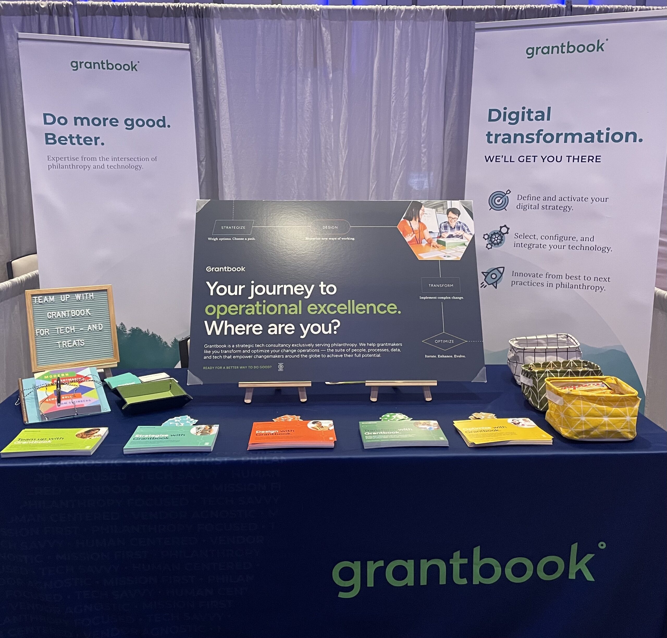 front view of Grantbook's conference booth depicting banners in the background and various displays on the table