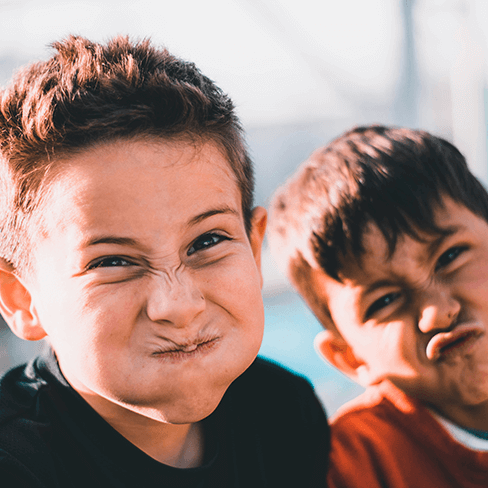 Two kids making silly faces, looking at the viewer