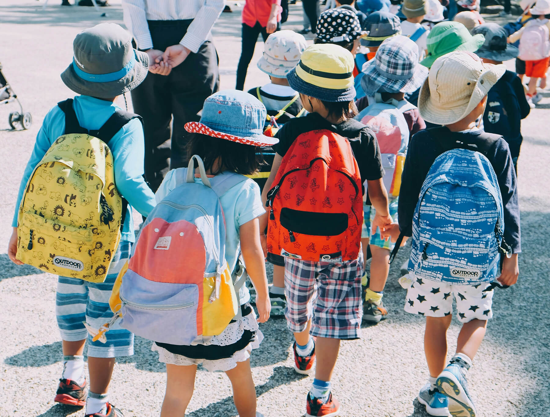 A group of young kids walking, wearing backpacks.